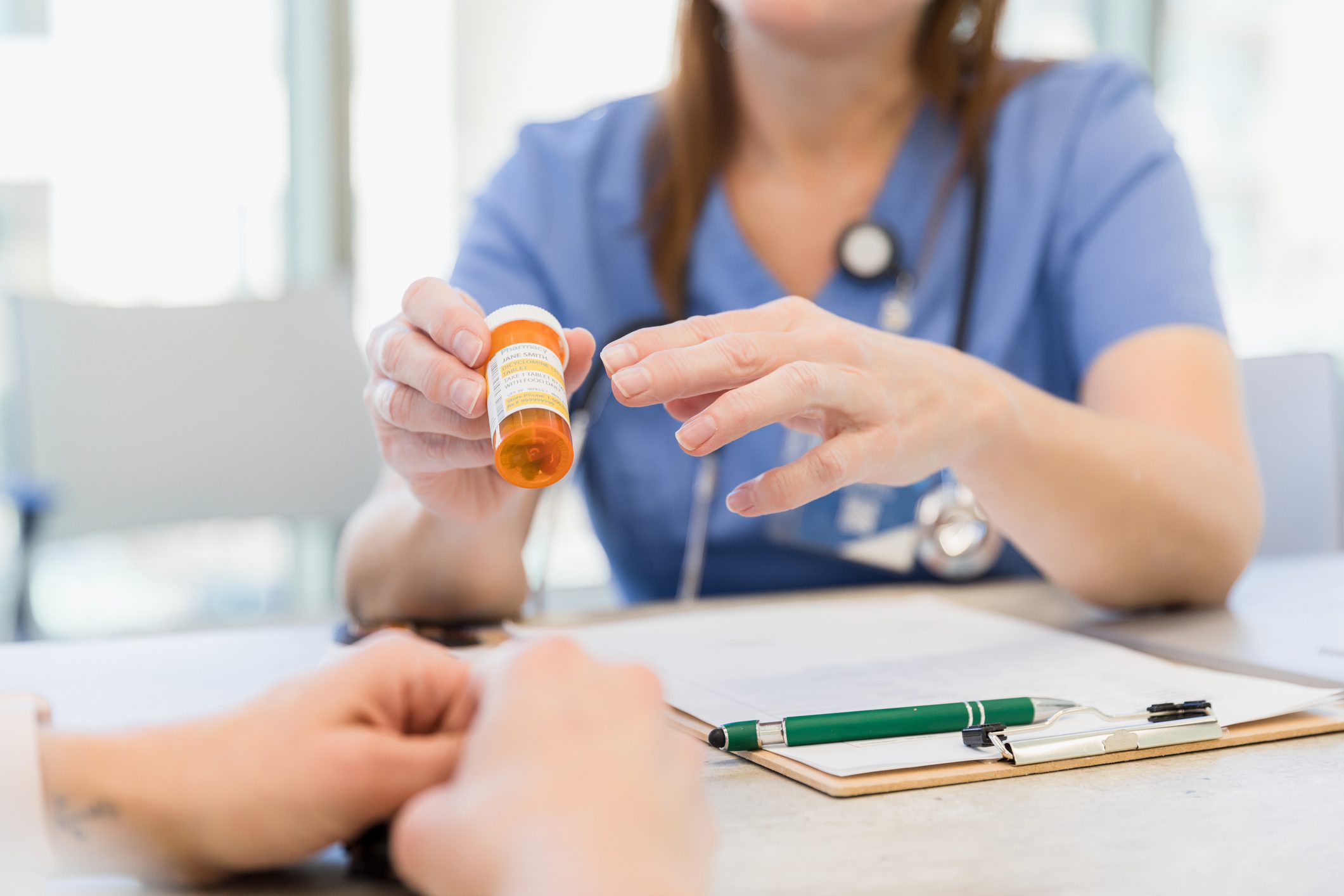 Nurse handing over prescription medication bottle.