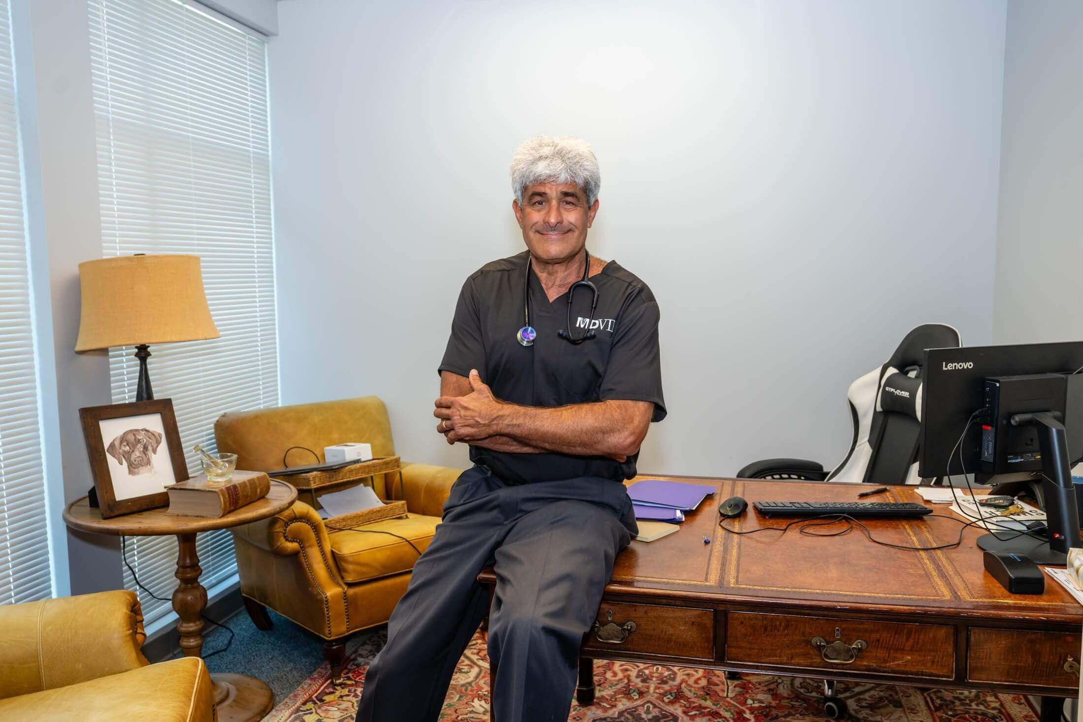 Man sitting on desk in office.