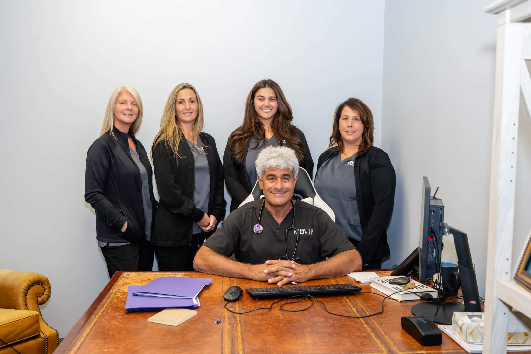 Five people posing in an office setting.